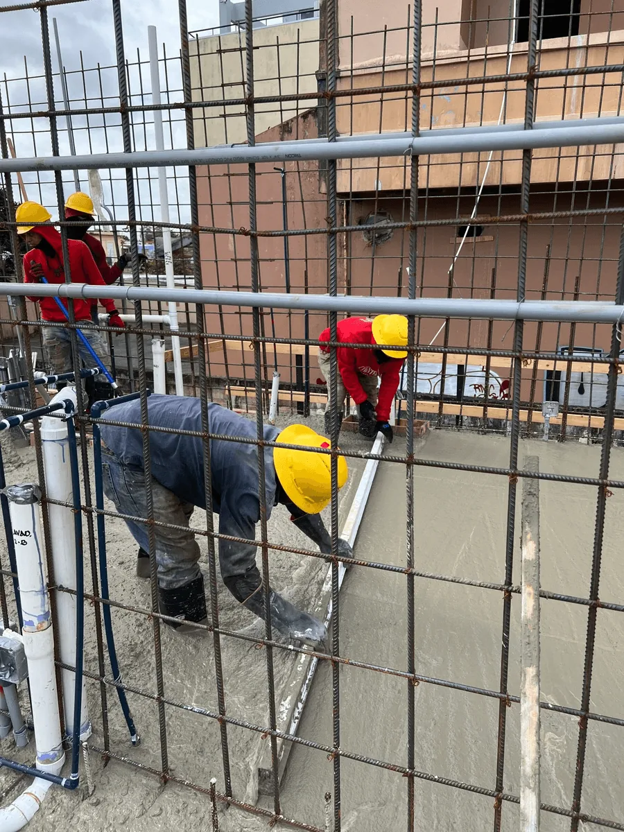 Obreros colocando acero de refuerzo y encofrado en una pared de hormigón